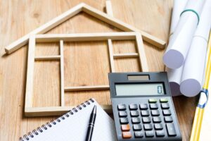 Valutazione dei costi di ristrutturazione casa con calcolatrice e progetti.